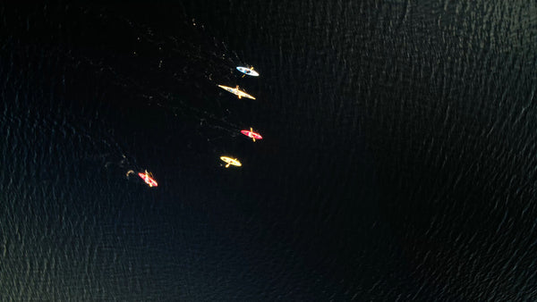 Kayaks gliding on dark water in Luleå - drone aerial view