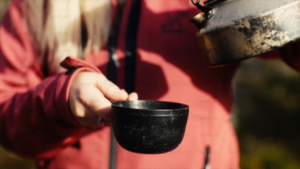 Hot berry juice poured into cup on sunny autumn day in Luleå forest