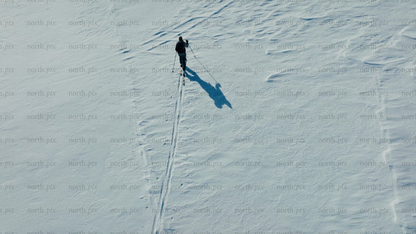 Skier crosses snowy mountain on sunny winter day
