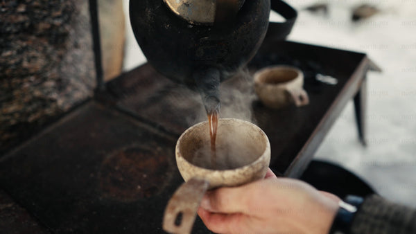 Pouring hot coffee into kuksa in winter forest of Luleå