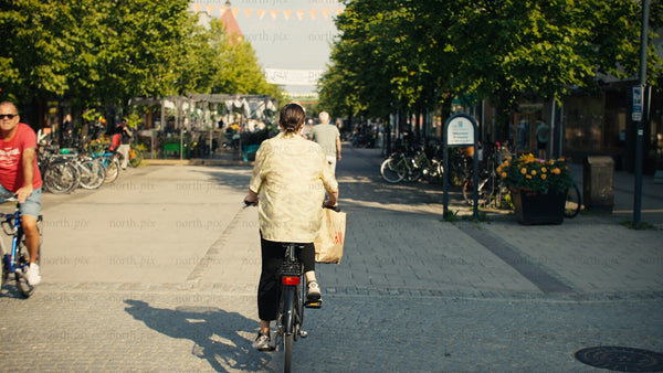 Woman on bicycle rides through Luleå city center on a sunny summer day
