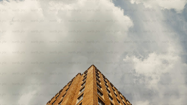 Low angle view of brick apartment building with slow upward camera movement and cloudy sky