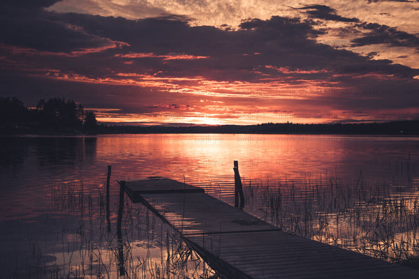 Wooden dock leading into lake at sunset