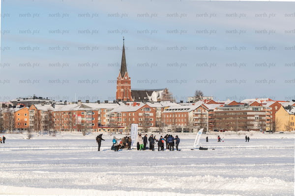 People on a frozen lake with town skyline, winter morning