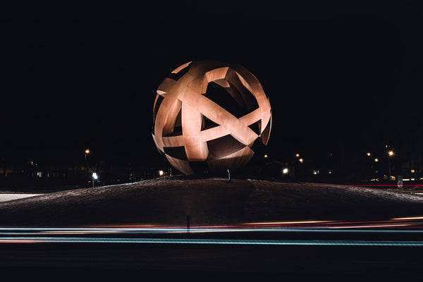 Large metal sphere sculpture on snowy roundabout at night