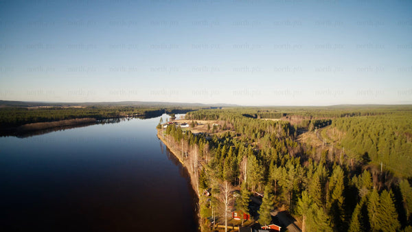View of Piteå's river and lush forest landscape under a clear blue sky