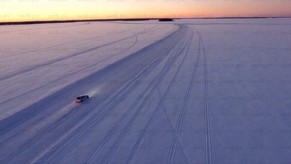 Car driving on ice road at sunset in Luleå archipelago