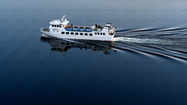 White passenger ferry sails on the Luleälven in Luleå on a summer day