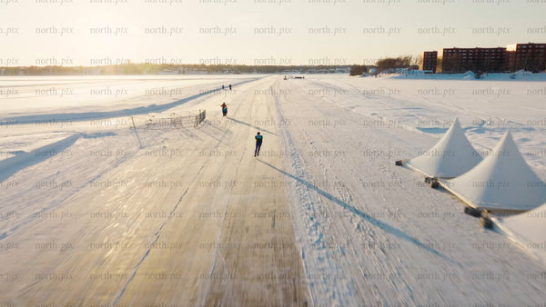 Ice skater on frozen track in Luleå during a bright winter day - drone footage