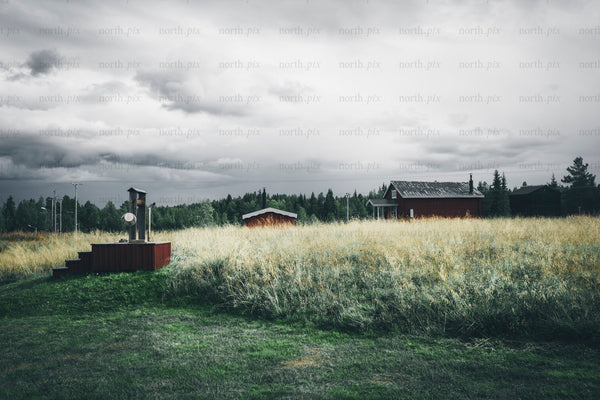Red house on grassy field, late summer overcast
