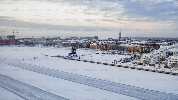 Winter in Luleå: Ice skating on a frozen lake at dusk - aerial view of cityscape