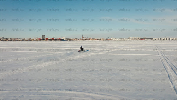 Snowmobile riding across frozen lake in Luleå - winter landscape