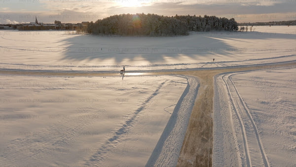 Winter Wonderland in Lulea, Sweden: Aerial View of Snowy Landscape at Sunset with Dog Walker