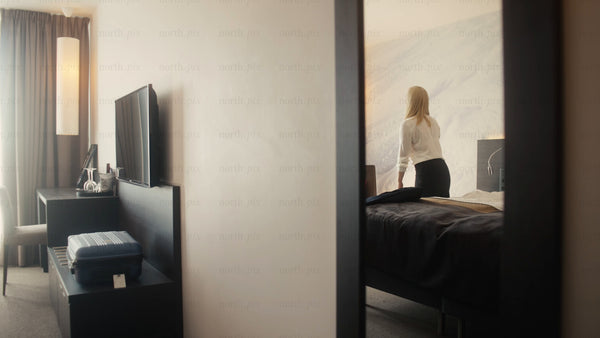 Businesswoman arriving in modern hotel room in Luleå, and relaxing on bed