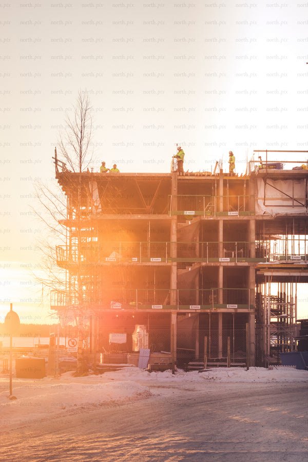 Construction site with workers at sunrise, winter