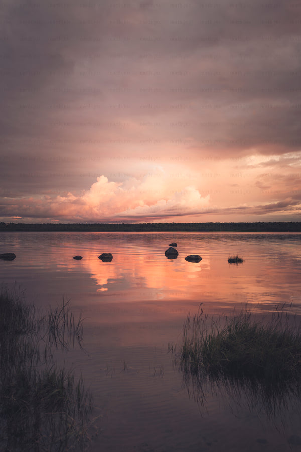 Rocks in lake at sunset with reflected clouds