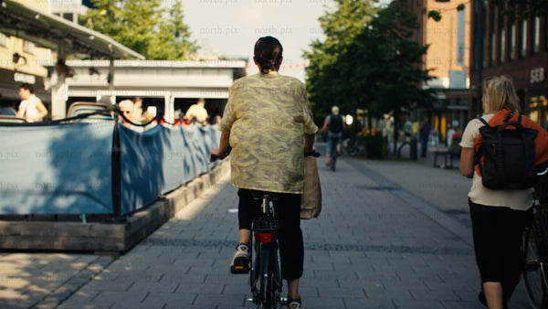 Woman on bicycle in Luleå city street during sunny summer day
