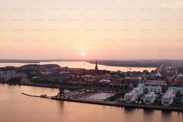 Sunset over Luleå city center by the riverfront with harbor cranes and modern housing