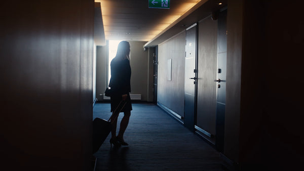 Businesswoman walking down dark hotel corridor and entering room