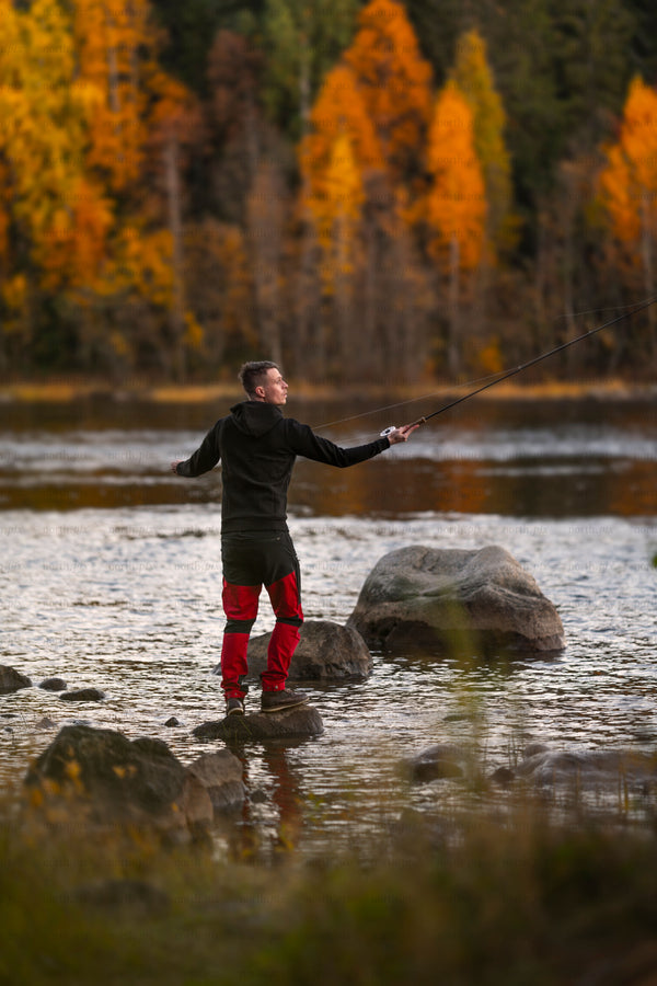 Man fly fishing on a river in autumn evening