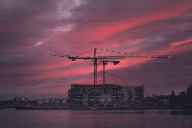 Construction cranes over waterfront building at dusk