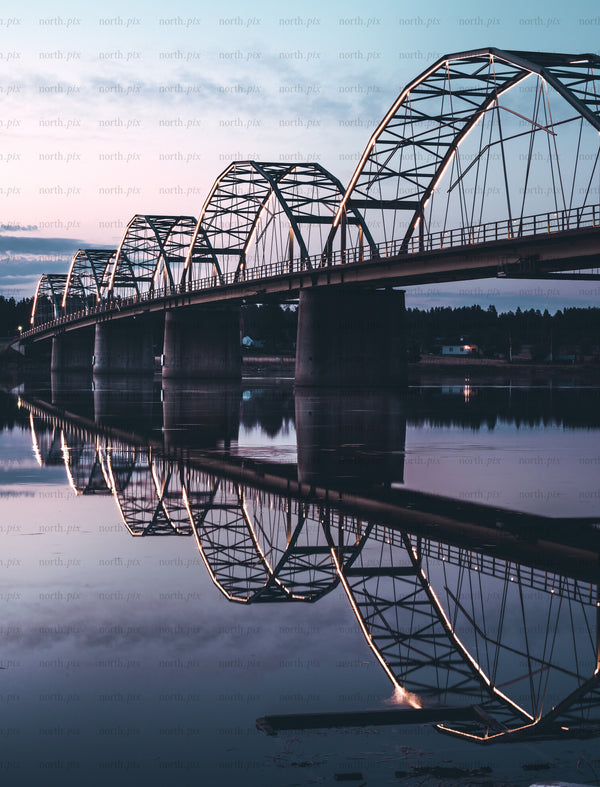 Arched steel bridge with reflection at dusk