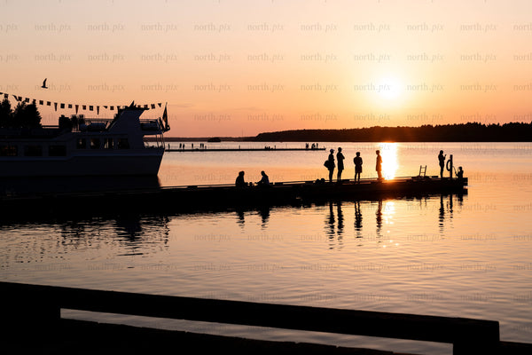 Silhouettes on pier at sunset over lake