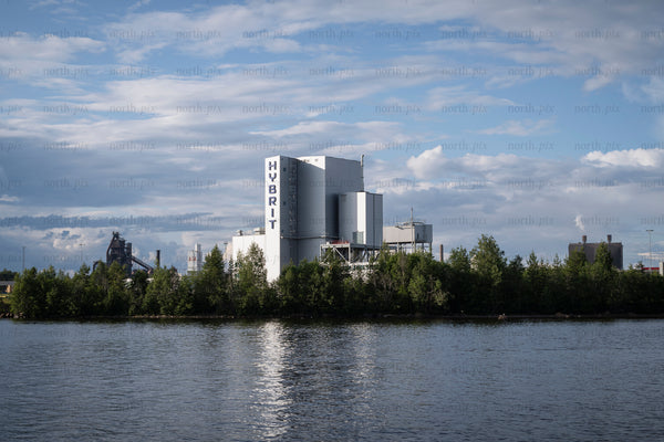 Industrial plant with HYBRIT signage by river in daytime
