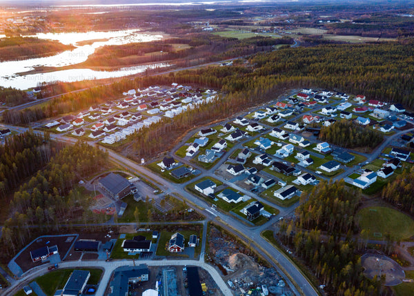 Aerial view of a suburban neighborhood amidst forests at sunset