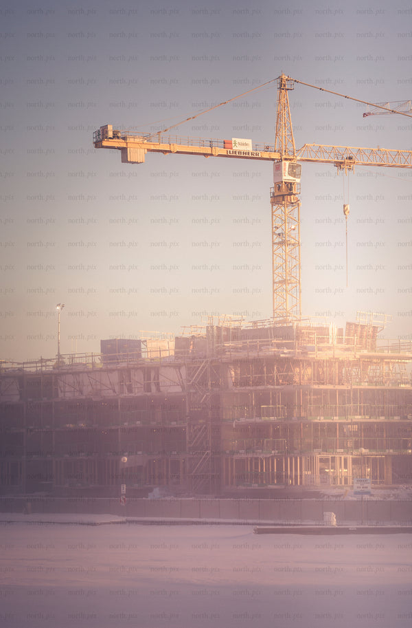 Tower crane over construction site at sunrise, winter