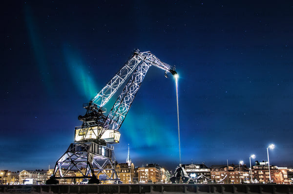 Industrial crane under Northern Lights over city harbor
