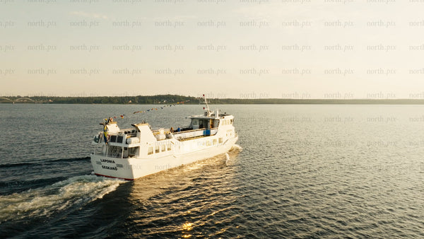 Luleå river cruise: White ferry sails at golden hour in summer