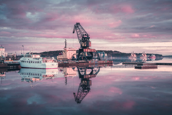 Industrial crane and boat reflected in harbor waters