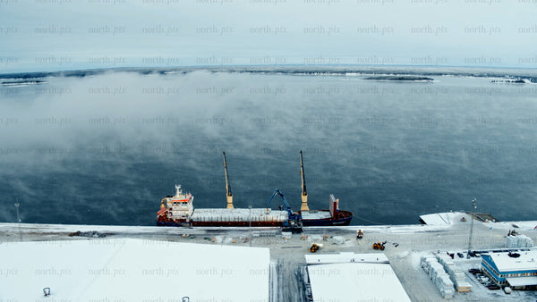 Aerial view of a cargo ship docked at Piteå Haraholmen harbour on a cold winter day