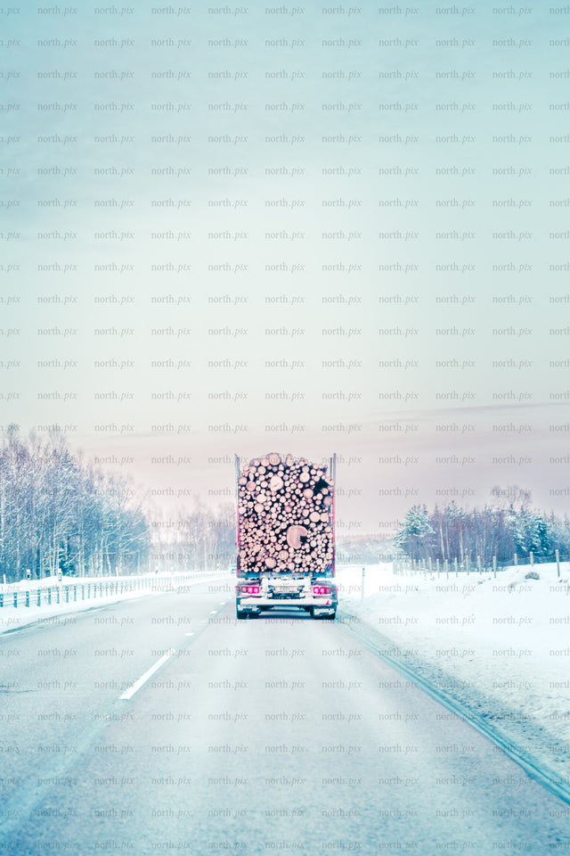 Log truck on snowy highway in winter morning