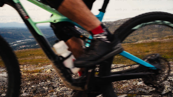 Mountain biker rides downhill on rocky trail in summer