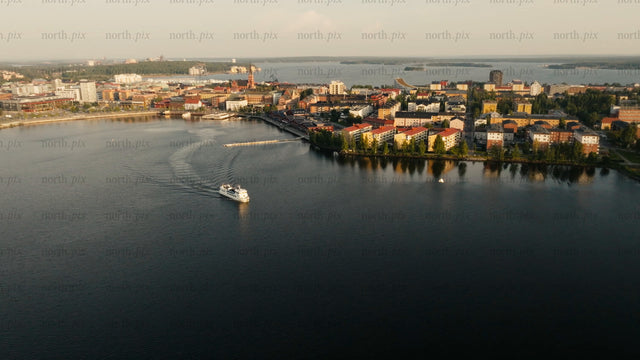 Aerial view of Luleå city on a summer evening: Boat tour, calm water, and sunset reflection