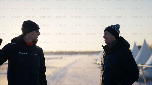 Two men talking on a frozen lake in Luleå during golden hour