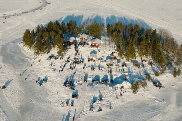 Aerial view of snowy island village with trees, tents, and visitors in Luleå city center