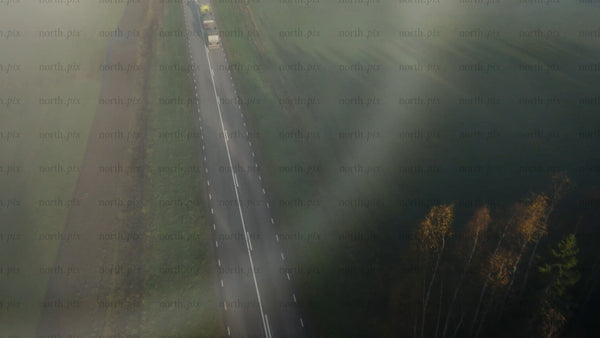 Misty road through rural countryside with autumn forest and fields