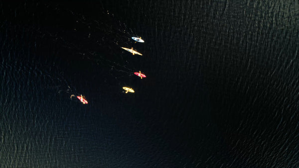 Kayaks gliding on dark water in Luleå - drone aerial view