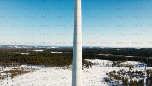 Wind turbine rotating in snowy landscape, Sweden, winter, green energy, aerial upward drone shot