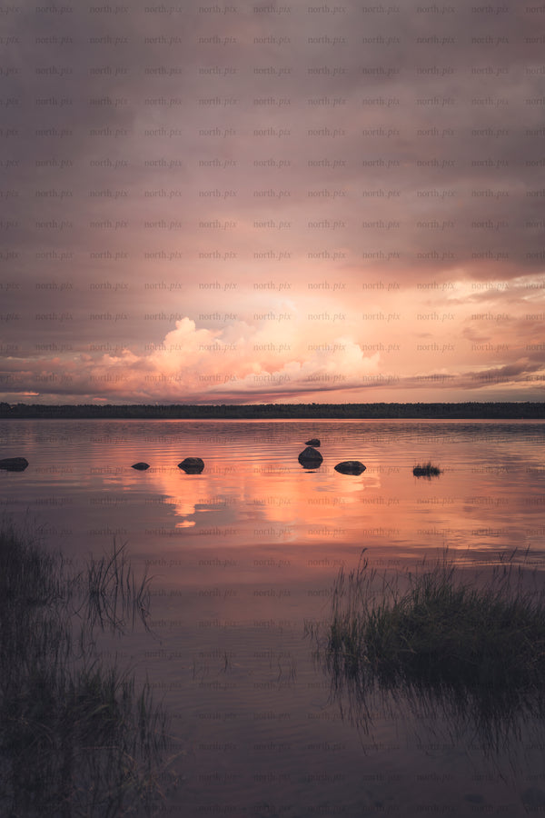Rocks in lake at sunset with reflected clouds