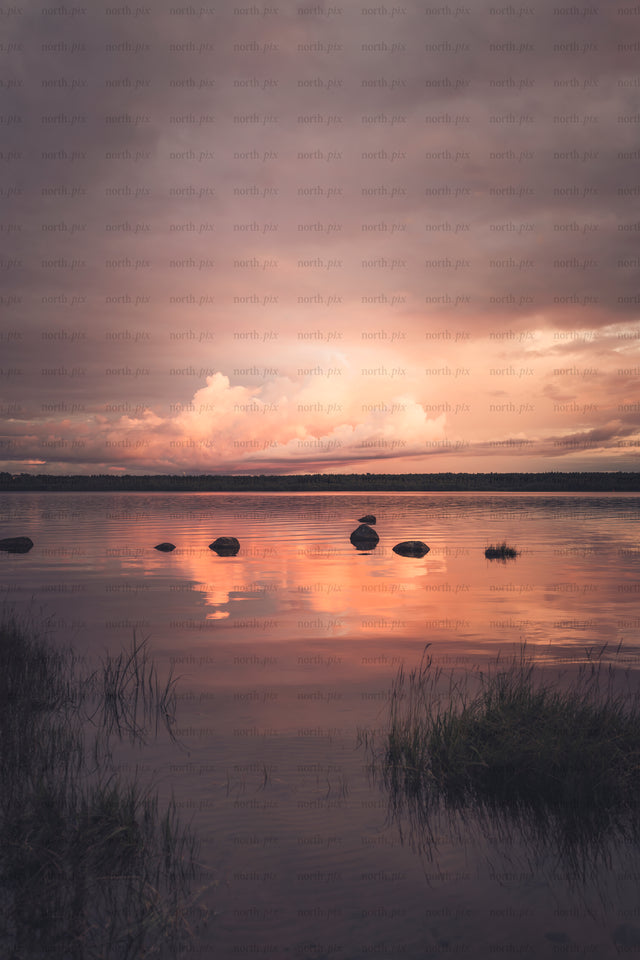 Rocks in lake at sunset with reflected clouds