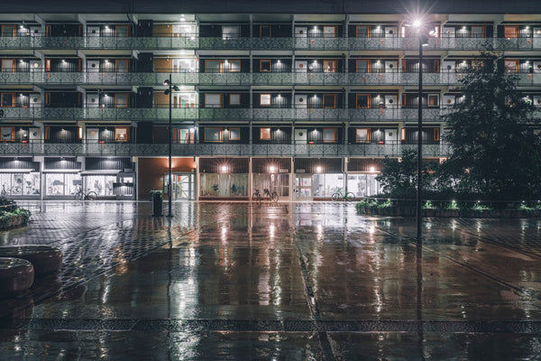 Apartment building facade at night with wet pavement