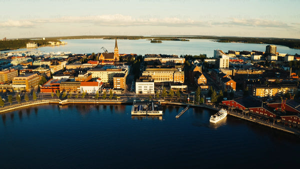 Aerial golden hour view of Luleå city center, waterfront restaurant, summer sunset
