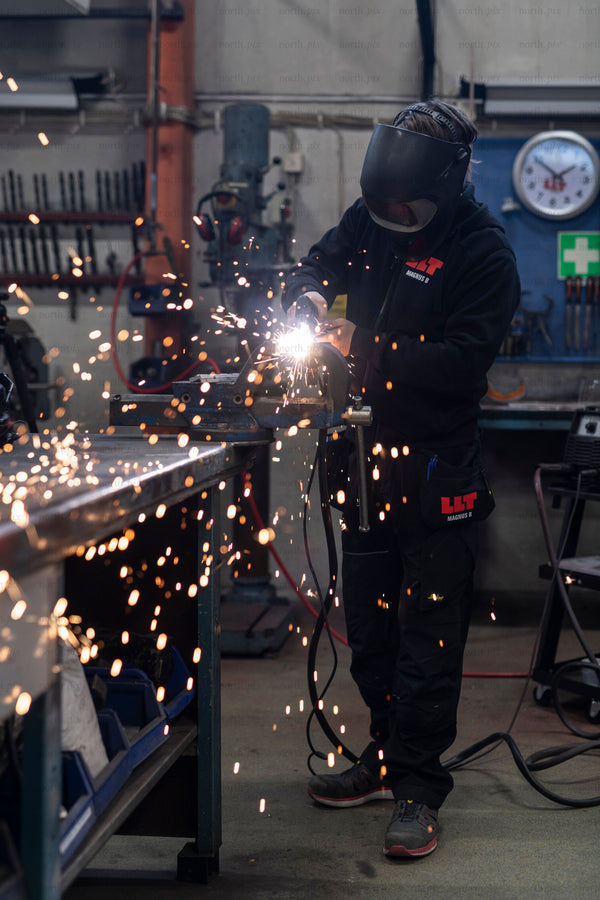 Worker welding metal in workshop with sparks