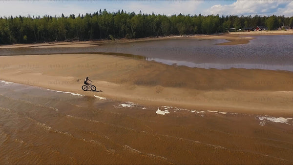 Fatbike rider in Sandön archipelago, Luleå: A summer day drone shot
