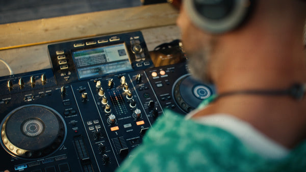 DJ mixing music on controller outdoors at sunset in Luleå