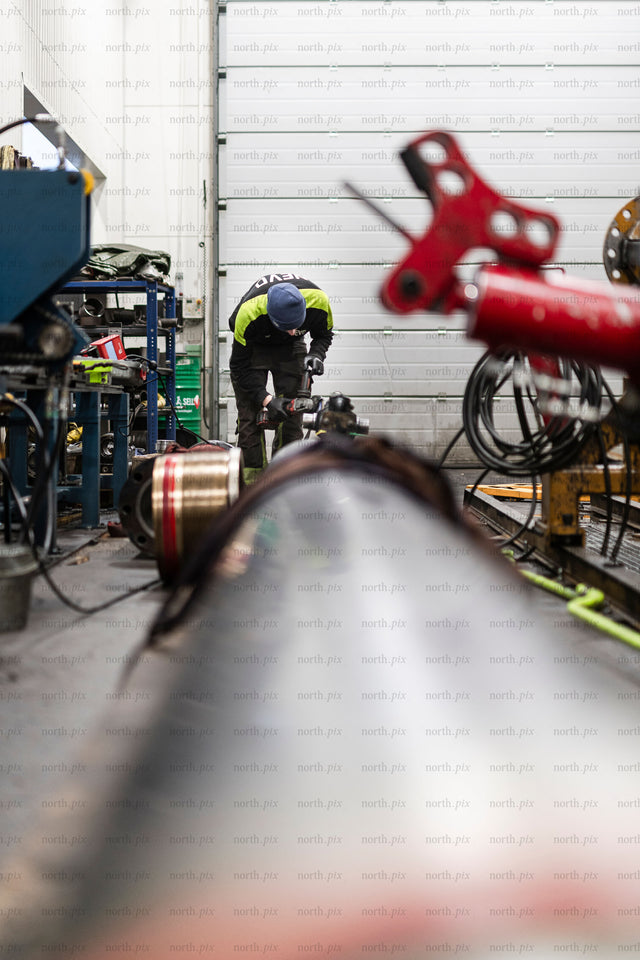 Worker repairing hydraulic pipe in industrial workshop